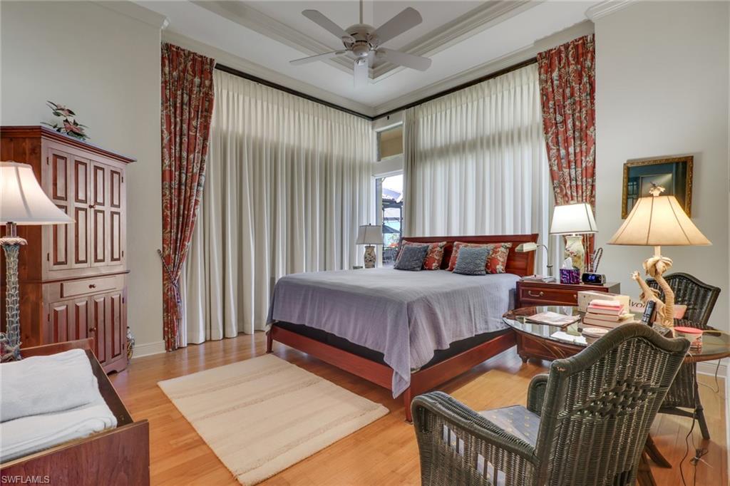 435 Terracina Way Naples, FL 34119 - Photo 23 of 50 Bedroom featuring ornamental molding, light wood-style flooring, a ceiling fan, a tray ceiling, and a high ceiling