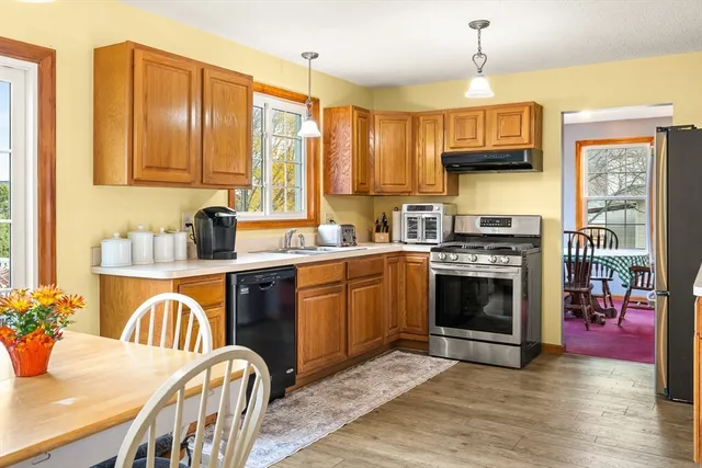 a kitchen with stainless steel appliances kitchen island granite countertop a table chairs and a refrigerator