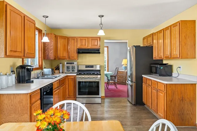 a kitchen with stainless steel appliances a stove a sink dishwasher and a refrigerator with wooden floor