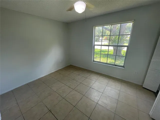 an empty room with chandelier fan and windows