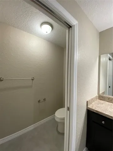 a bathroom with a granite countertop sink and a toilet