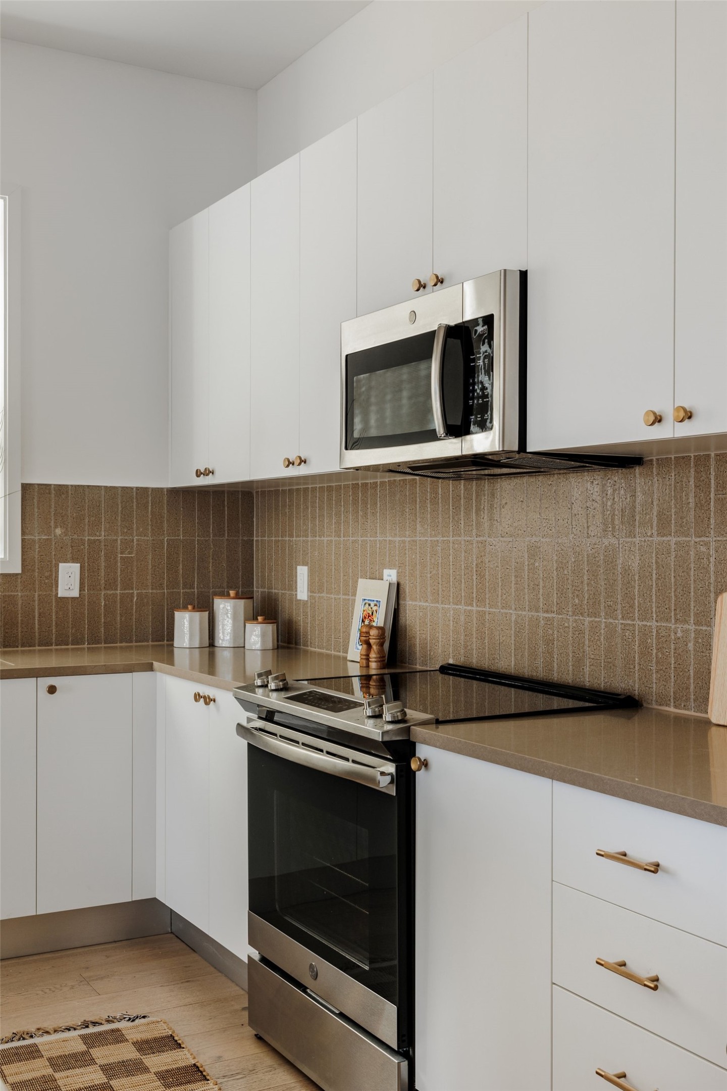 800 Embassy Drive, Unit 408 Austin, TX 78702 - Photo 11 of 30 Kitchen featuring stainless steel appliances, white cabinets, light wood-type flooring, and backsplash