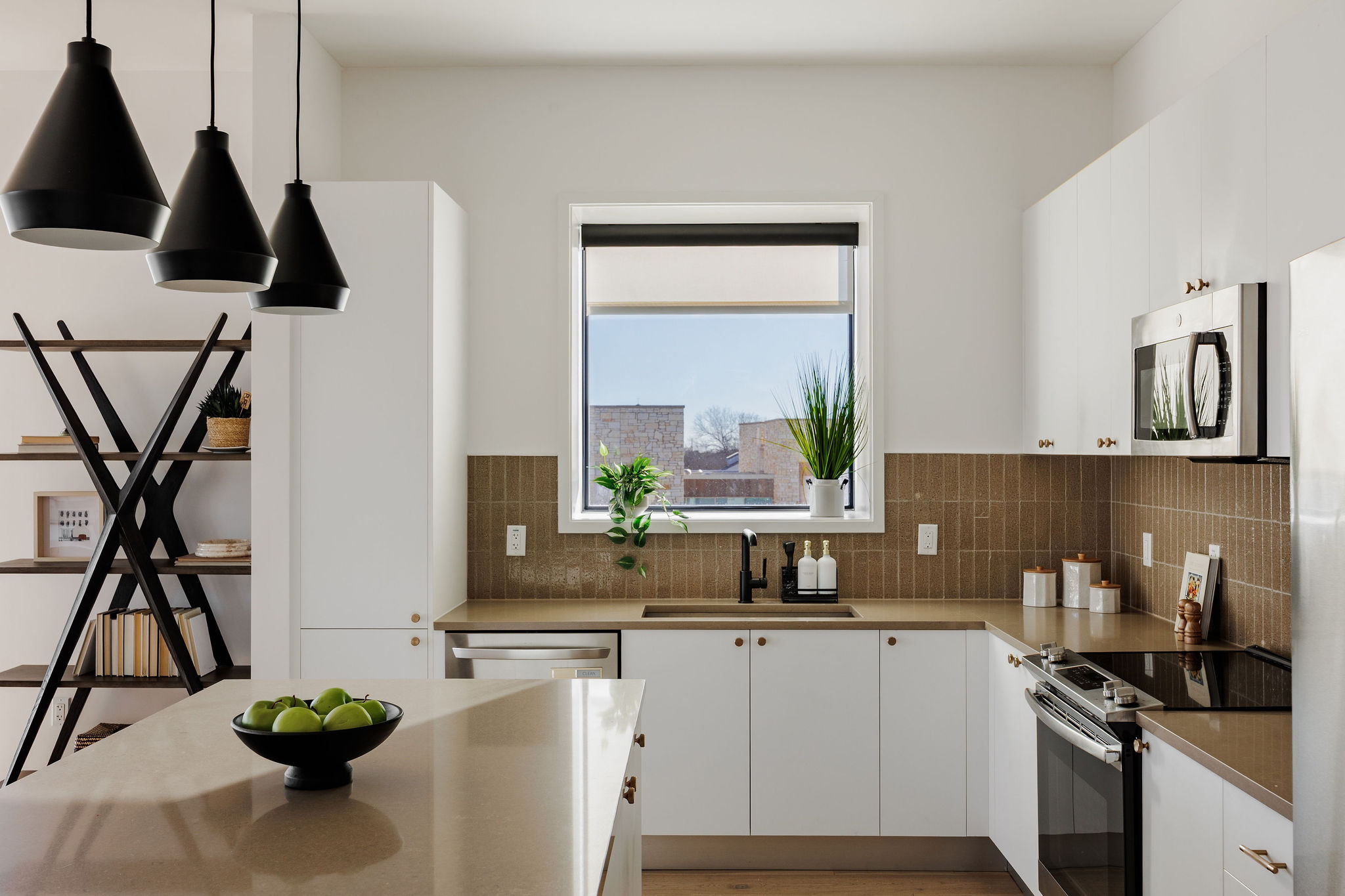 800 Embassy Drive, Unit 408 Austin, TX 78702 - Photo 12 of 30 Kitchen featuring stainless steel appliances, white cabinetry, hanging light fixtures, and light wood finished floors