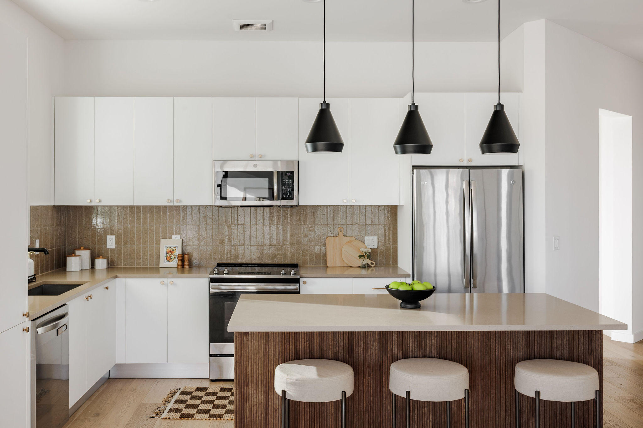 800 Embassy Drive, Unit 408 Austin, TX 78702 - Photo 8 of 30 Kitchen with appliances with stainless steel finishes, hanging light fixtures, white cabinetry, a breakfast bar area, and decorative backsplash