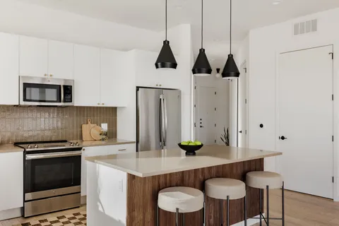 a kitchen with stainless steel appliances a dining table chairs and stove