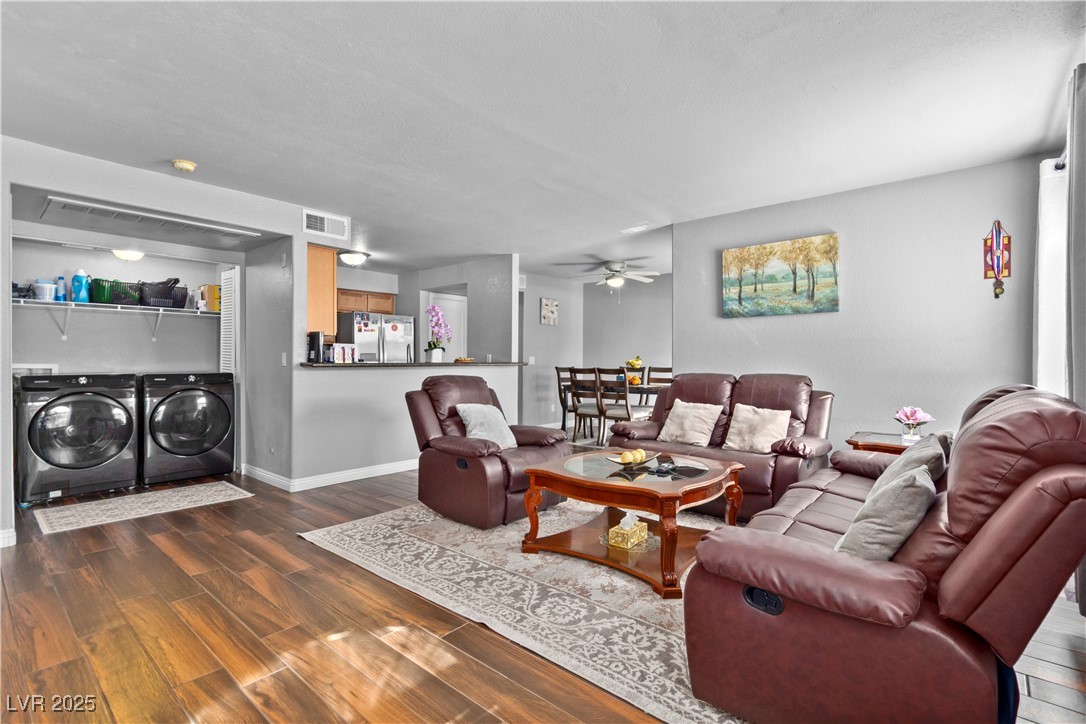 Living room with dark tile finished floors, ceiling fan, and energy save washer and clothes dryer