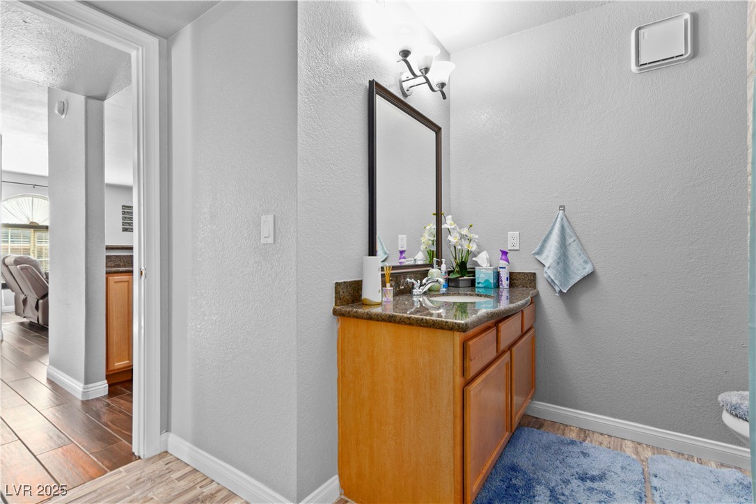 9325 West Desert Inn Road, Unit 141 Las Vegas, NV 89117 - Photo 13 of 30 Bathroom with a textured wall, light wood-style flooring, and vanity