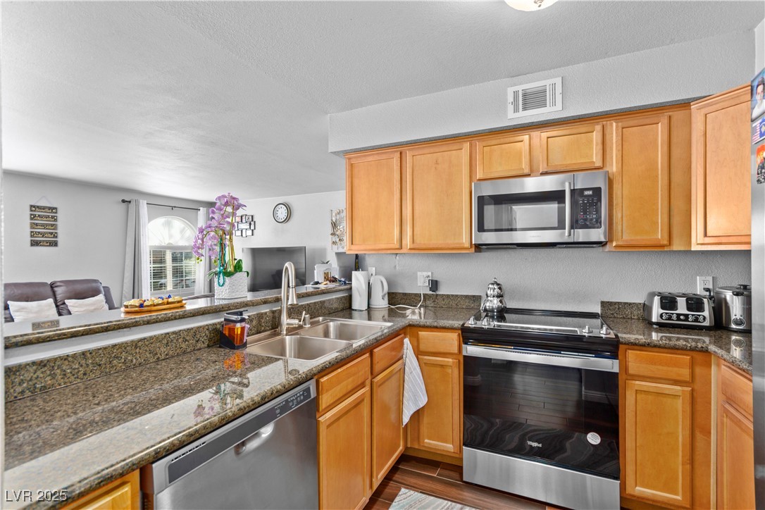 9325 West Desert Inn Road, Unit 141 Las Vegas, NV 89117 - Photo 29 of 30 Kitchen featuring appliances with stainless steel finishes, dark wood-type flooring, dark stone counters, open floor plan, and a textured ceiling