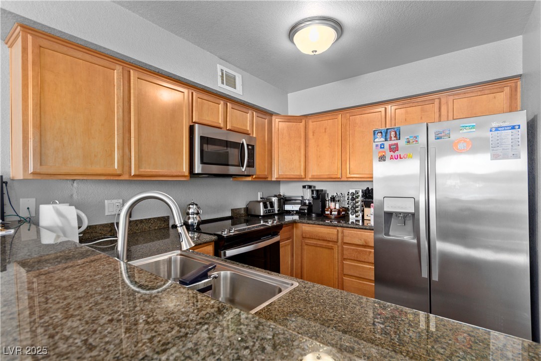 9325 West Desert Inn Road, Unit 141 Las Vegas, NV 89117 - Photo 4 of 30 Kitchen featuring stainless steel appliances, dark stone countertops, and a textured ceiling