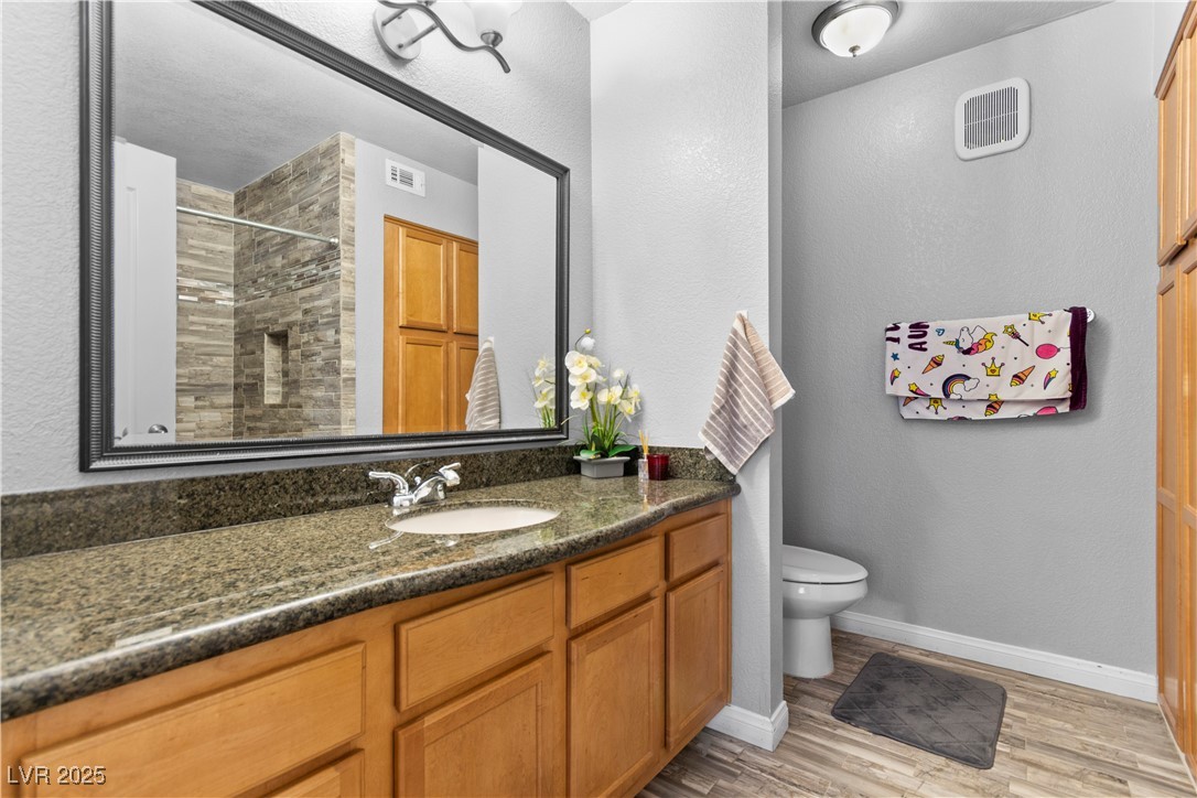 9325 West Desert Inn Road, Unit 141 Las Vegas, NV 89117 - Photo 8 of 30 Full bath with a textured wall, vanity, a shower stall, and light wood finished floors