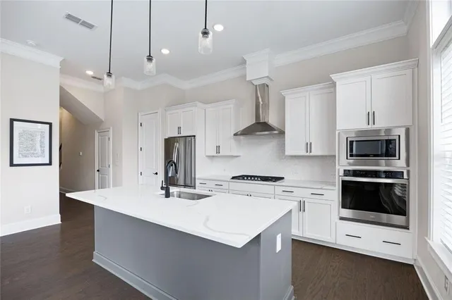 a kitchen with stainless steel appliances a sink a stove a refrigerator cabinets and a center island