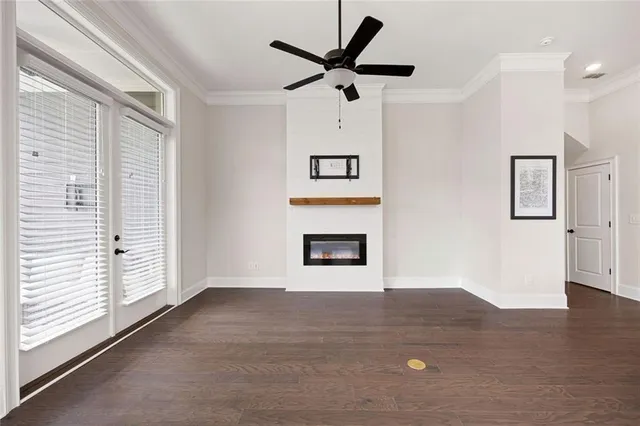 a view of a livingroom with a fireplace a ceiling fan and wooden floor