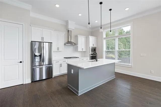 a large kitchen with stainless steel appliances granite countertop a sink a stove a refrigerator and a wooden floor