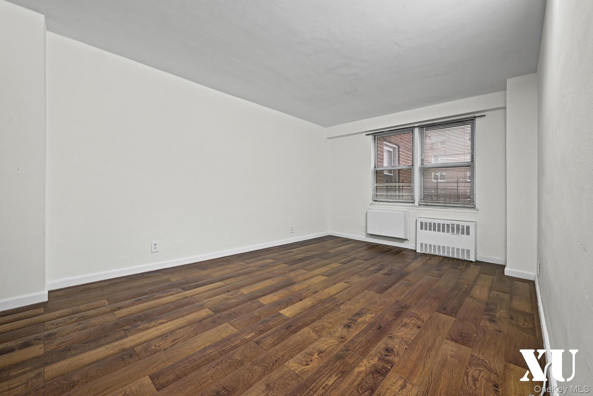 43-10 Kissena Boulevard, Unit 2B Queens, NY 11355 - Photo 12 of 23 an empty room with wooden floor and windows