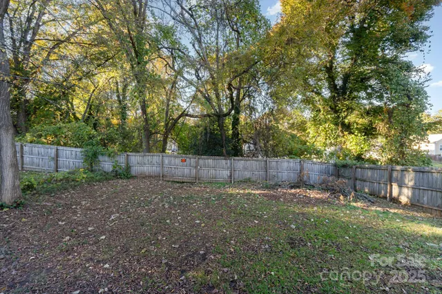 a view of a backyard with a trees and wooden fence