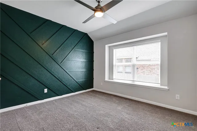 an empty room with a ceiling fan and window