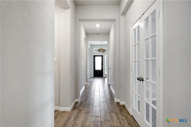 a view of a hallway with wooden floor and a bathroom