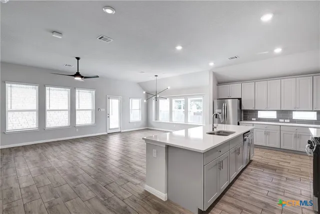 a large kitchen with stainless steel appliances granite countertop a large counter top and a wooden floors