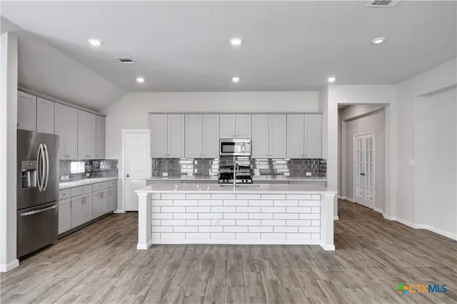 a large kitchen with stainless steel appliances granite countertop a large center island a stove a refrigerator and a cabinets