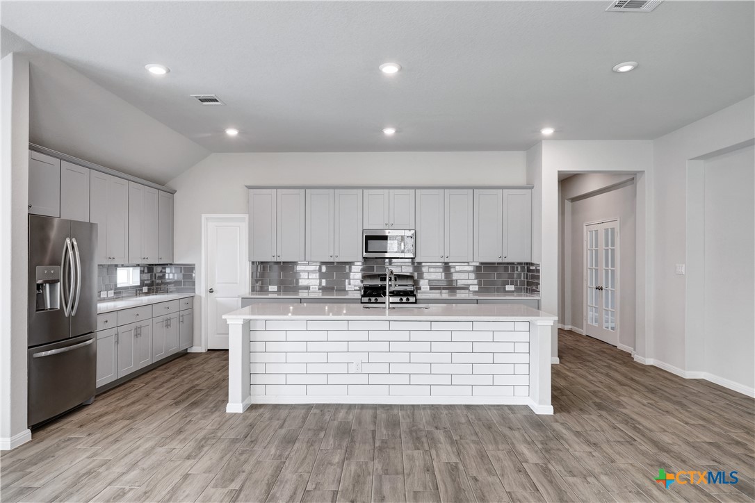 32144 Cardamom Way Bulverde, TX 78163 - Photo 5 of 30 a large kitchen with stainless steel appliances granite countertop a large center island a stove a refrigerator and a cabinets