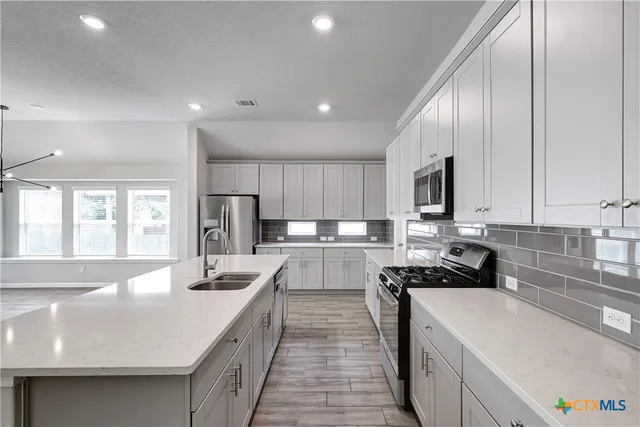 a view of a kitchen with kitchen island a sink a counter top space stainless steel appliances and cabinets