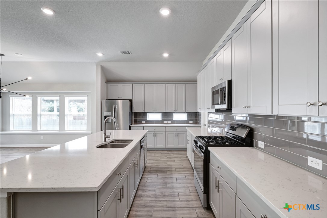 32144 Cardamom Way Bulverde, TX 78163 - Photo 6 of 30 a view of a kitchen with kitchen island a sink a counter top space stainless steel appliances and cabinets