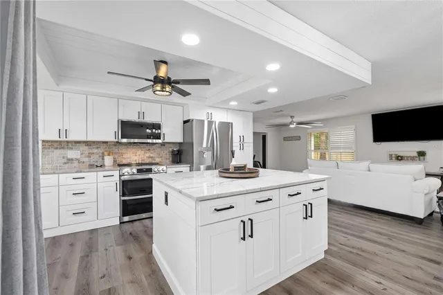 a kitchen with stainless steel appliances a stove top oven a sink dishwasher and white cabinets with wooden floor