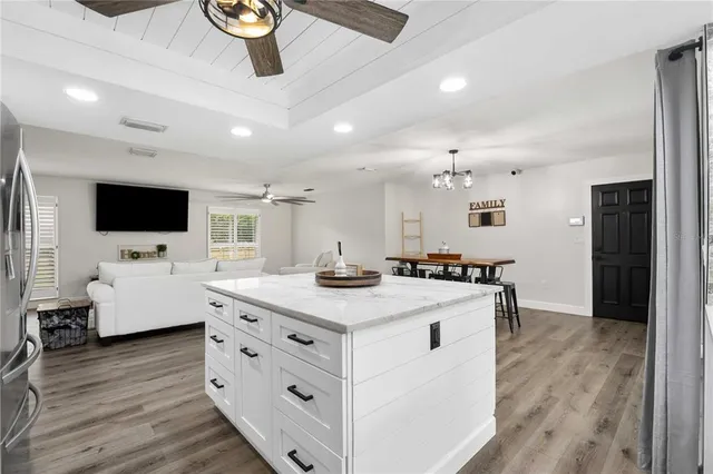 a kitchen with stainless steel appliances kitchen island wooden floors granite counter tops and white cabinets