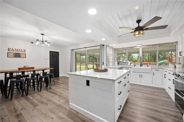 a kitchen with kitchen island granite countertop a island in the center windows and a sink