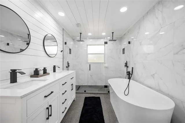 a spacious bathroom with a double vanity sink a mirror a bathtub and a shower
