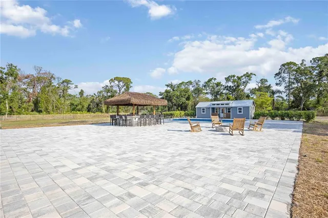 a view of swimming pool with lawn chairs and plants