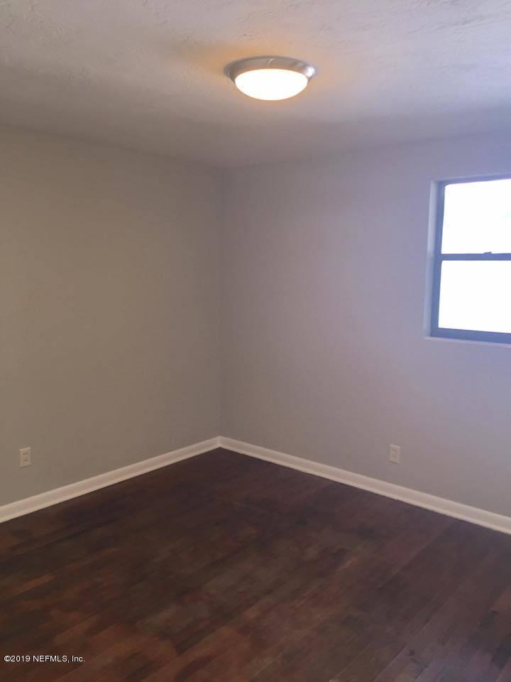 5107 Spring Glen Road Jacksonville, FL 32207 - Photo 4 of 16 an empty room with wooden floor and windows