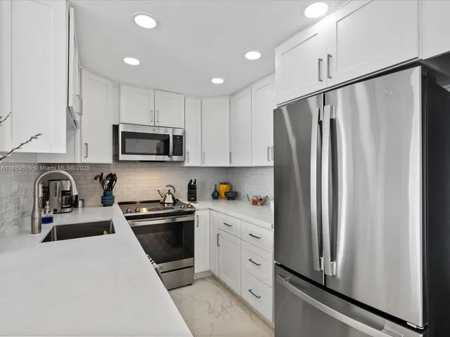 a kitchen with stainless steel appliances granite countertop a refrigerator sink and stove