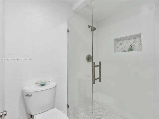 a white toilet sitting next to a shower