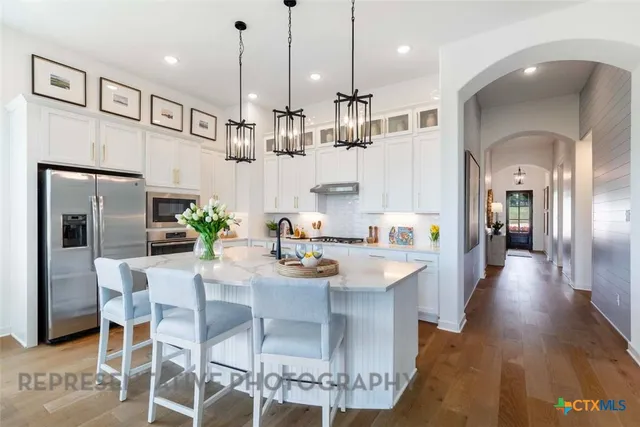 a kitchen with stainless steel appliances kitchen island granite countertop a refrigerator and a view of living room
