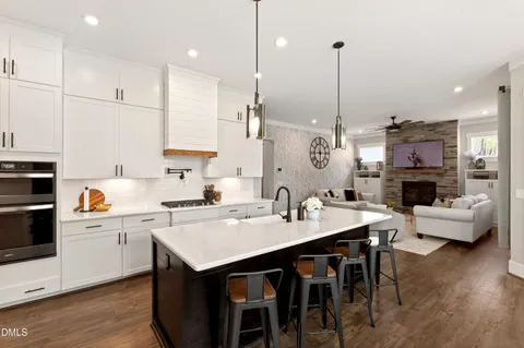 a kitchen island with stainless steel appliances a sink a stove a table and chairs