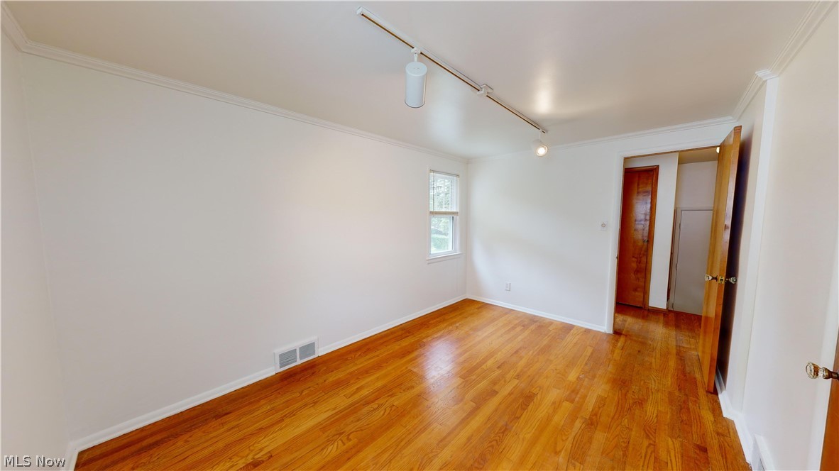 1508 Edgefield Road Lyndhurst, OH 44124 - Photo 16 of 28 Empty room with crown molding, light wood-type flooring, and rail lighting