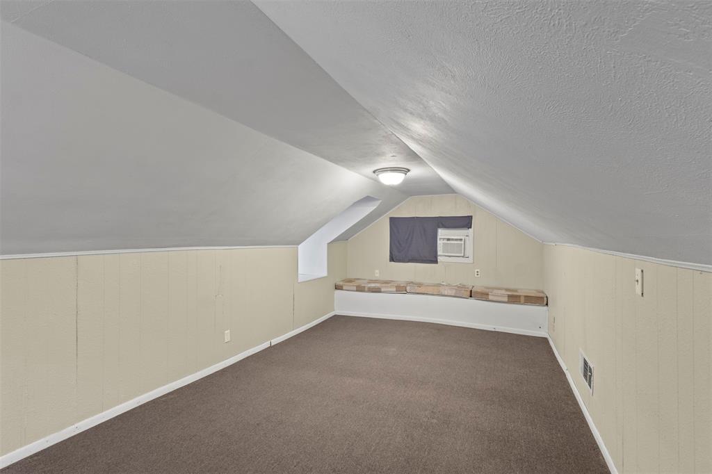 829 West 9th Street Bonham, TX 75418 - Photo 23 of 30 Attic space featuring sloped ceilings, paneling, and brown carpet flooring