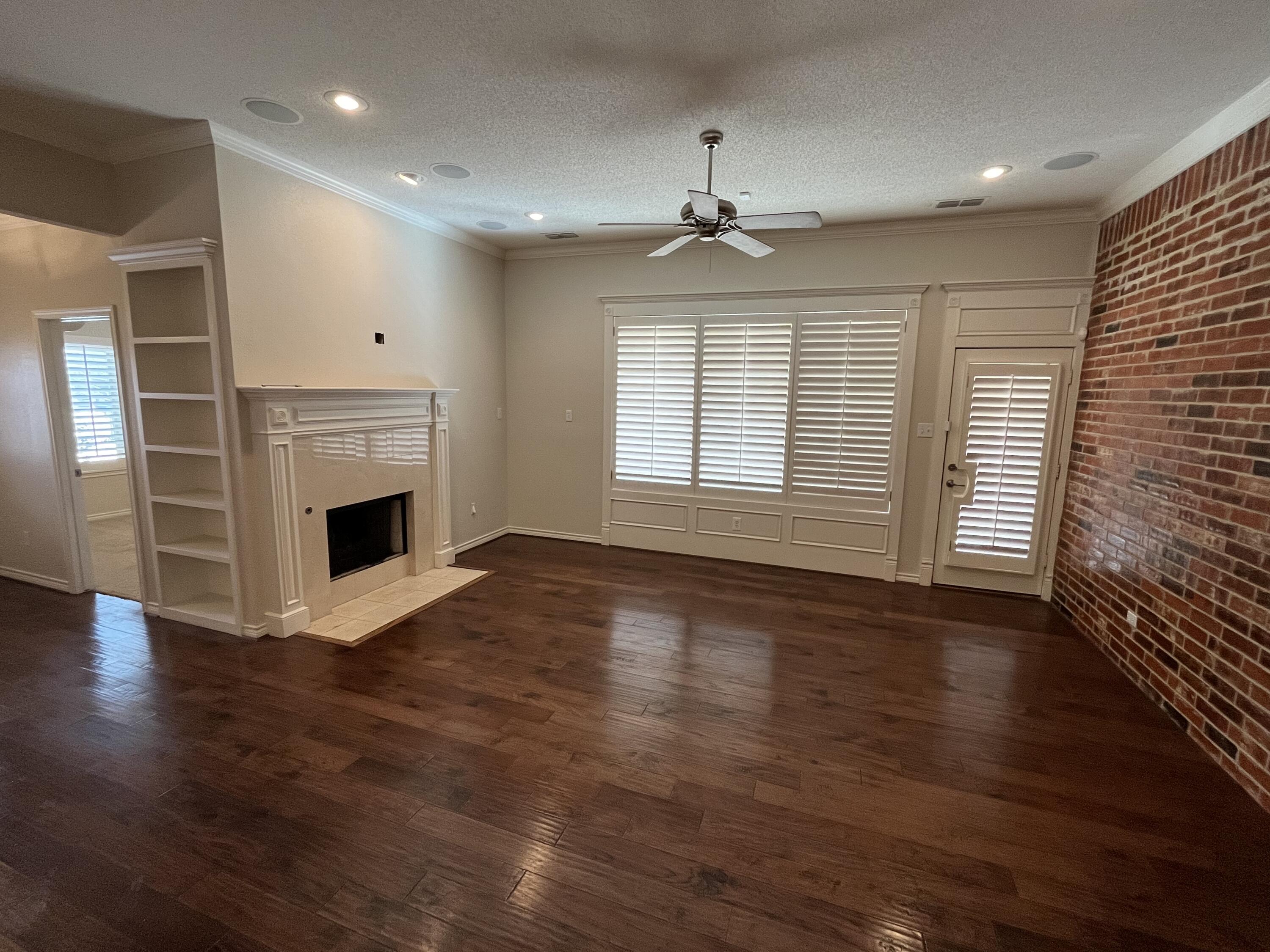 10602 Wayne Avenue Lubbock, TX 79424 - Photo 2 of 17 an empty room with wooden floor fireplace and windows
