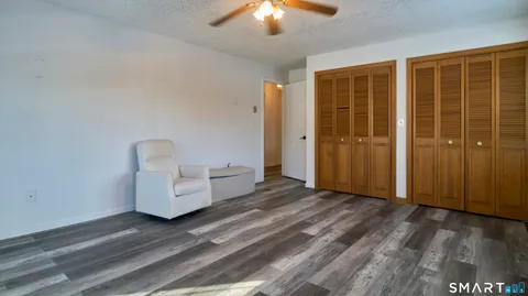 an empty room with wooden floor closet and windows
