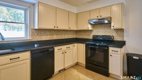 a kitchen with granite countertop white cabinets and black appliances