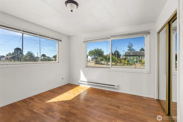a view of empty room with wooden floor and fan