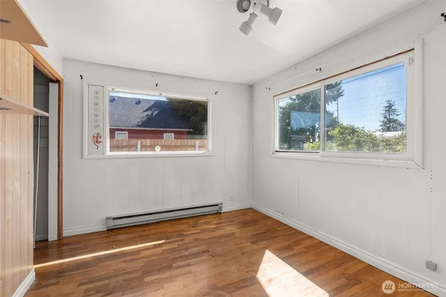a view of empty room with wooden floor and fan