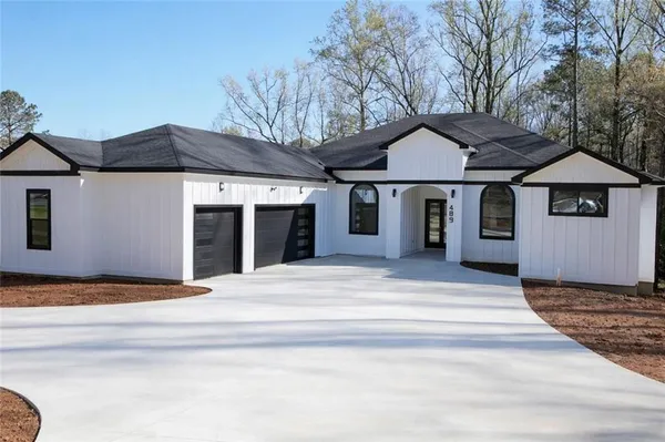 a front view of a house with a garden and trees