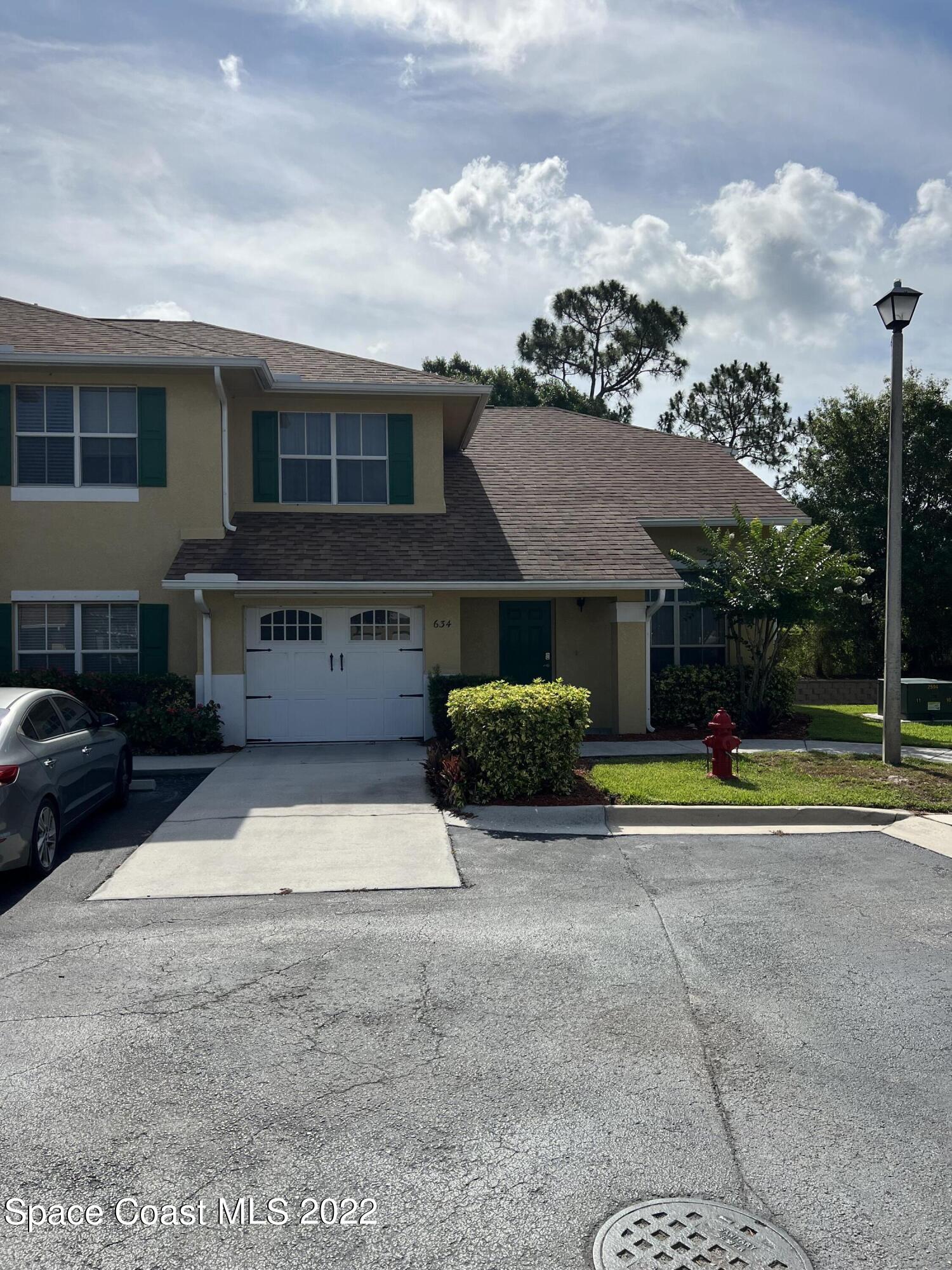 a view of a house with a yard and a car park side of the road