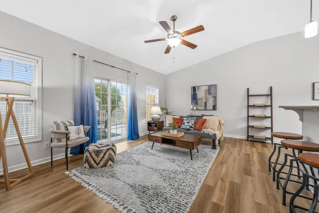a living room with furniture kitchen view and a wooden floor