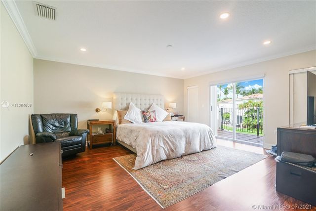 a spacious bedroom with a bed a couch and wooden floor