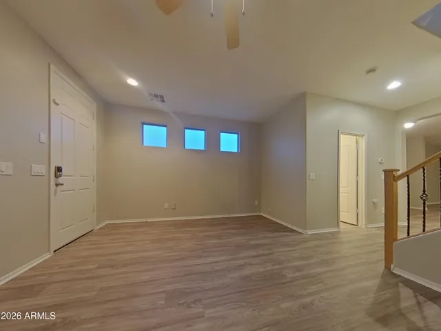 a view of an empty room with wooden floor and a ceiling fan