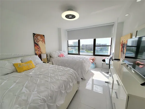 a bedroom with a bed and a flat tv screen next to a window