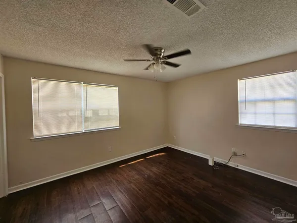 a view of empty room with wooden floor and fan